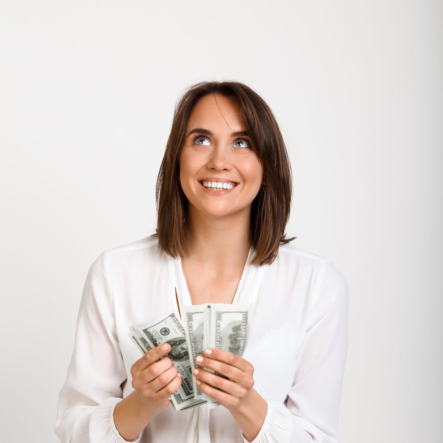 Portrait of young successful business woman smiling, holding money, over white background.